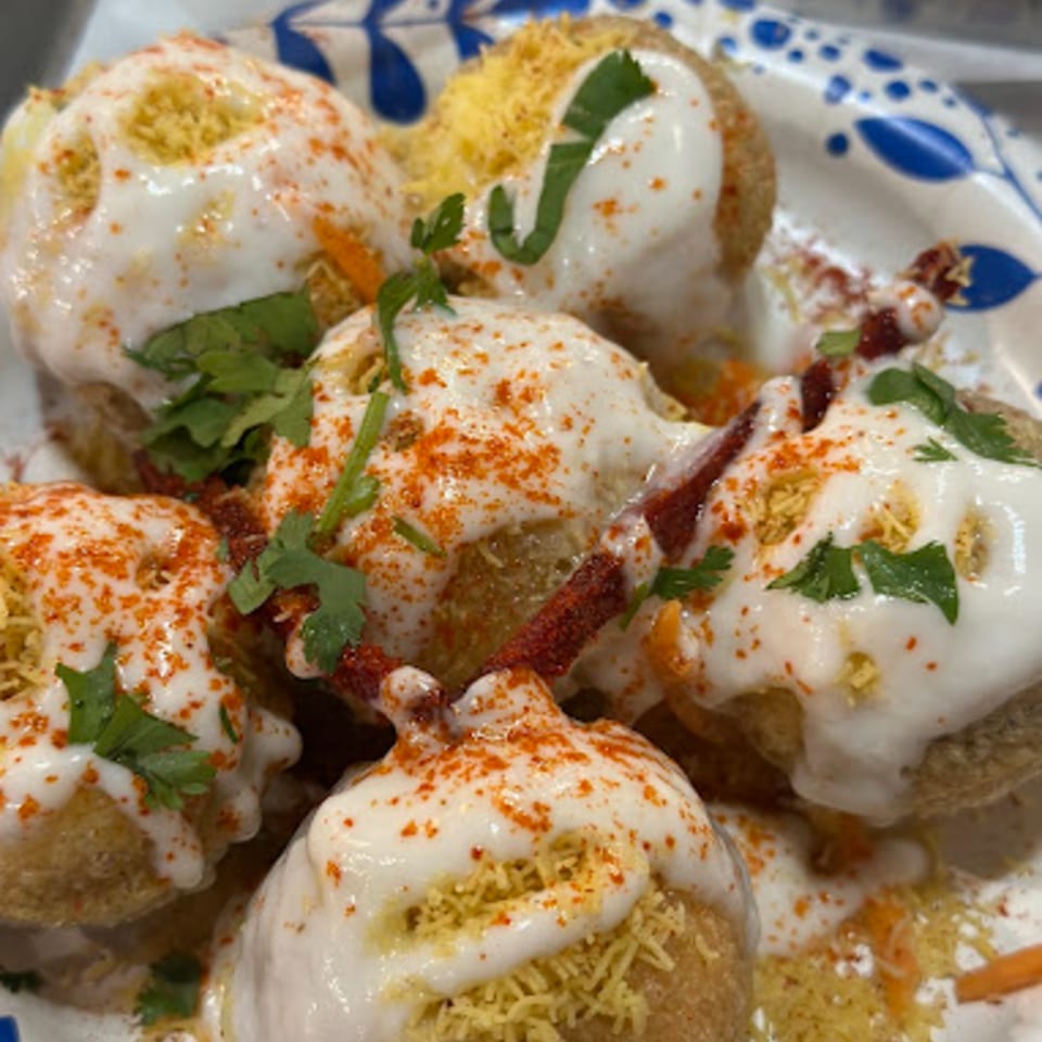 Close-up of Indian dahi puri, topped with yogurt, red chili powder, sev, and cilantro.