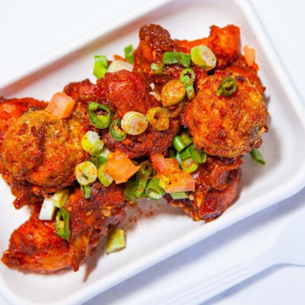 Spicy Indian vegetarian dish with red sauce, green onions, and diced tomatoes in a white dish.
